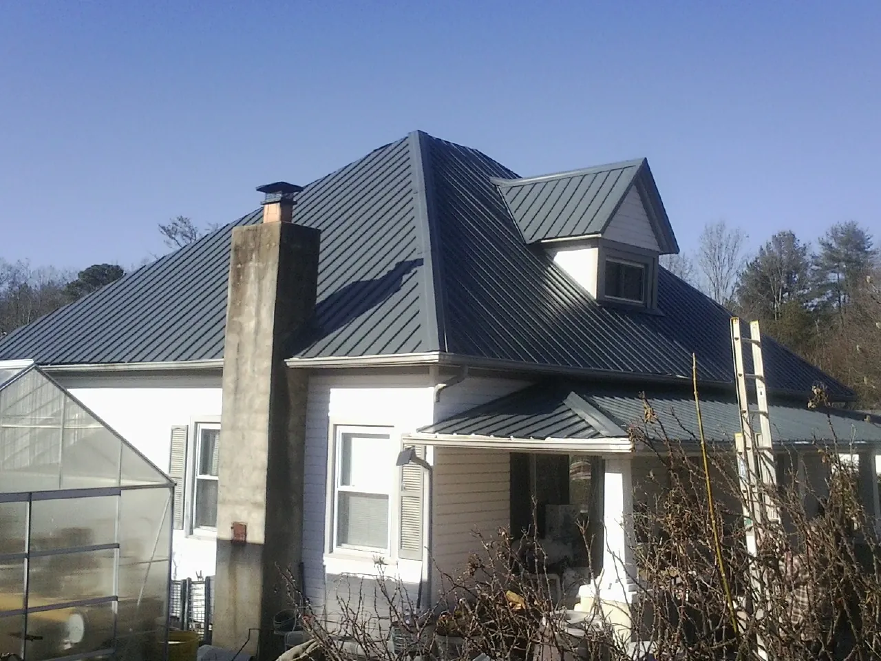 Dark blue standing seam metal roof on a white farmhouse with dormer — Slate & Tile Roof Repair by Roofing Brothers in Grass Valley