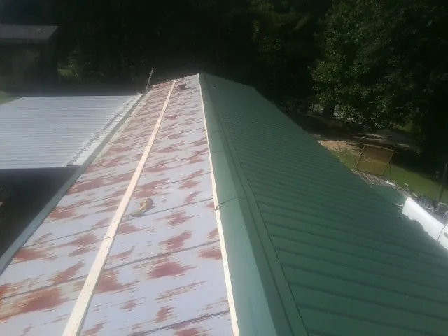 Old rusted panels beside newly installed green metal roofing — Wind Damage Roof Repair by Roofing Brothers in Grass Valley