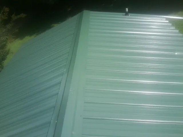 New green metal panels meeting at the ridge of a roof — Flat Roof Repair work by our crew in Grass Valley