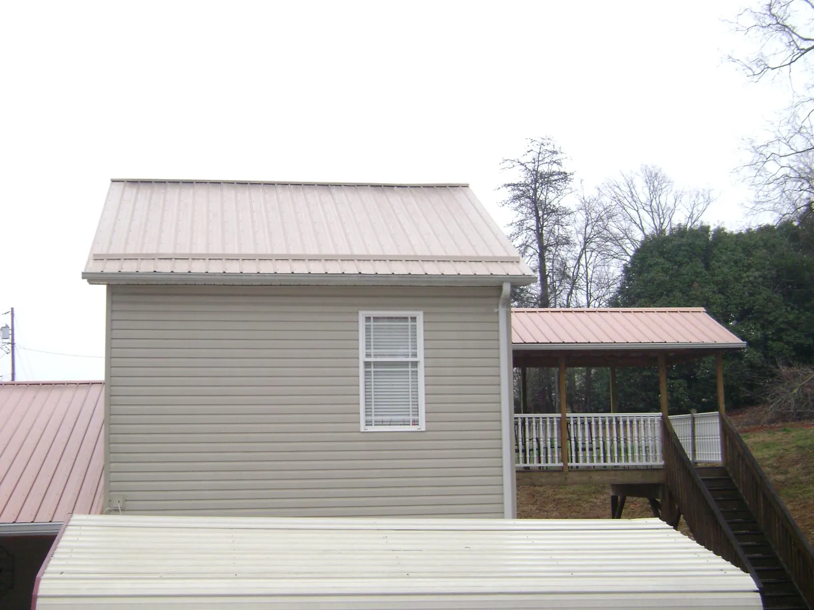 Tan metal roofs on a two story addition and attached porch, from a Roof Replacement job in Grass Valley